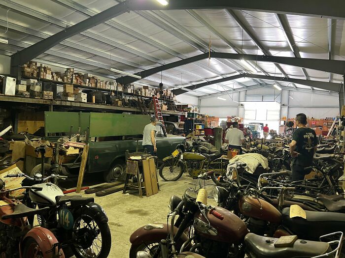 Spacious warehouse filled with vintage motorcycles and old treasures waiting for antique lovers to explore.