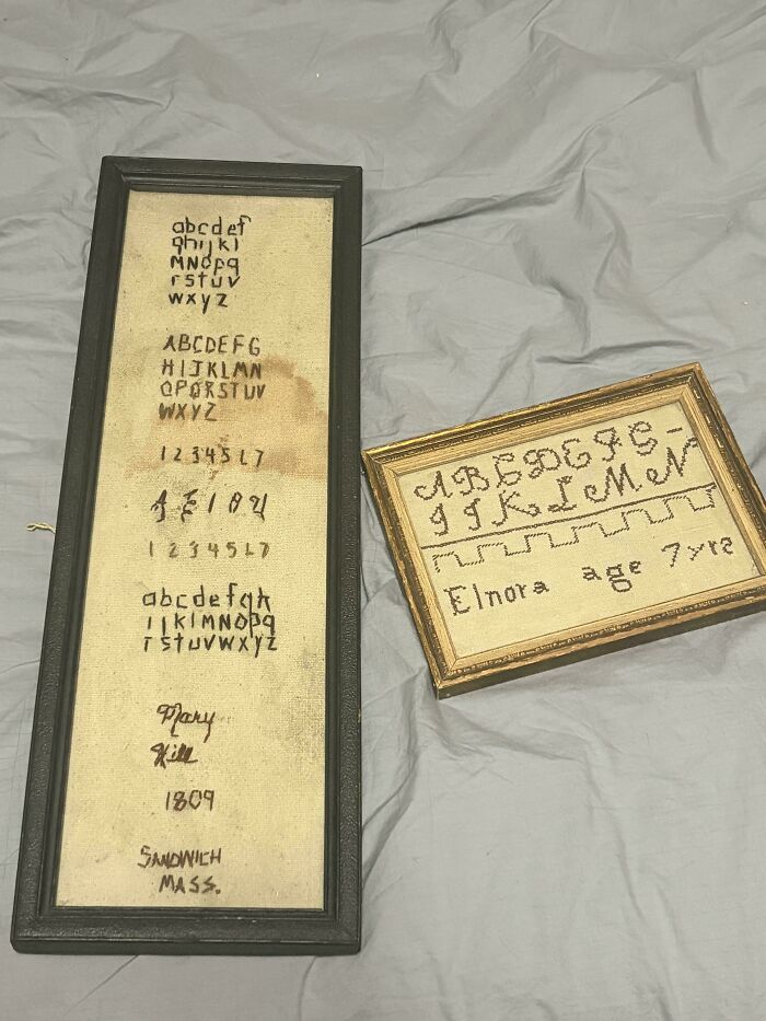 Framed antique needlework samplers displaying stitched alphabets, cherished as old treasures.