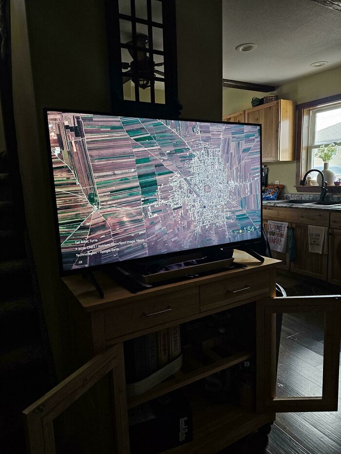 A television displaying a satellite map looks like a glitch in the matrix in a dimly lit kitchen.