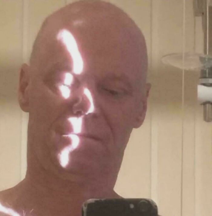 A man's face with a bright, wavy light pattern, making it look like a glitch in the matrix.
