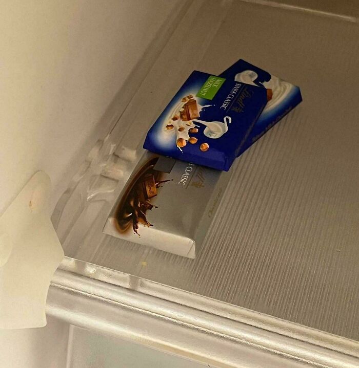Two chocolate bars appear to be floating on a shelf, creating a visual glitch in the matrix due to reflection.