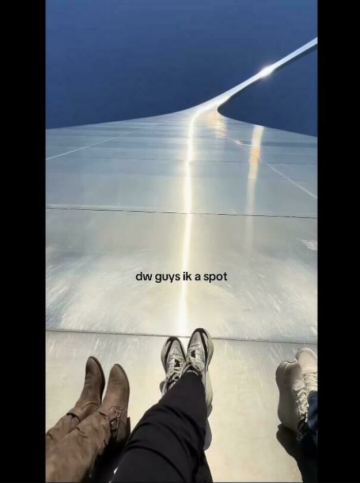 A high-angle view of two pairs of feet on a shiny surface reflecting the sky, creating a glitch in the matrix optical illusion.