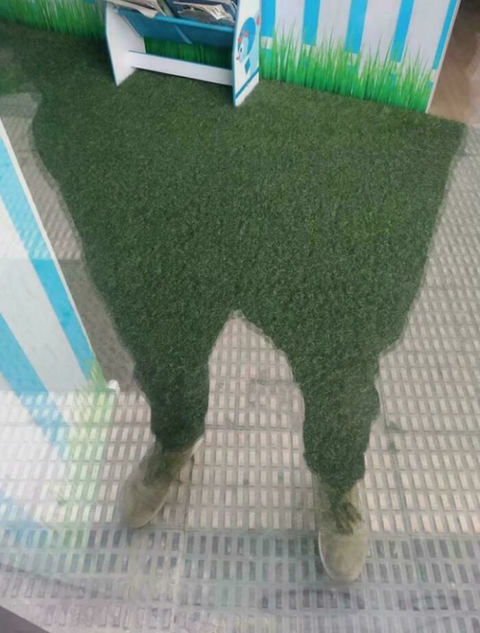A person's legs appearing to blend into artificial grass, creating a visual glitch in the matrix effect.
