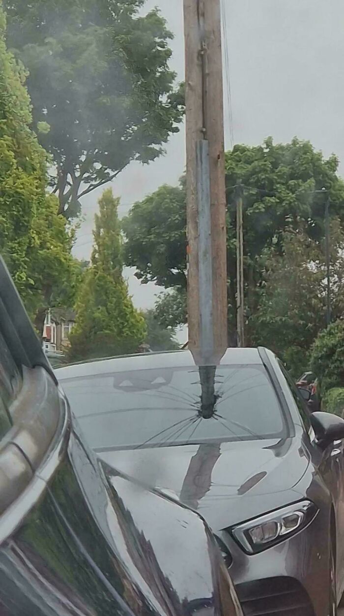 A utility pole appears to have pierced a car windshield, creating a glitch in the matrix effect.