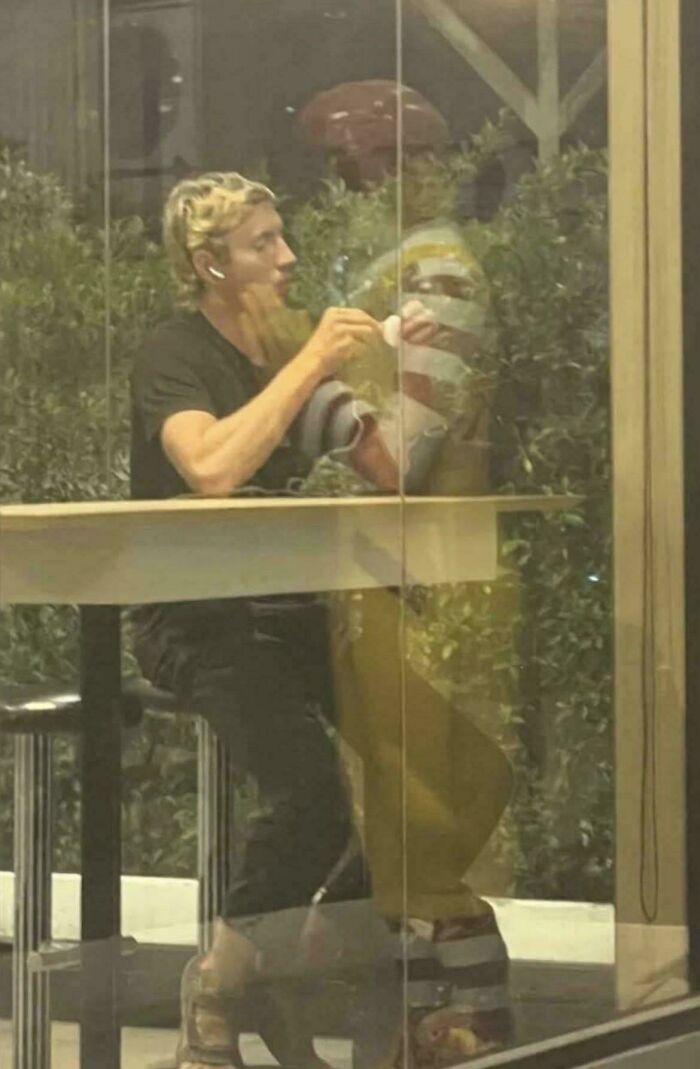A man seen through a window with a reflection that looks like a glitch in the matrix.