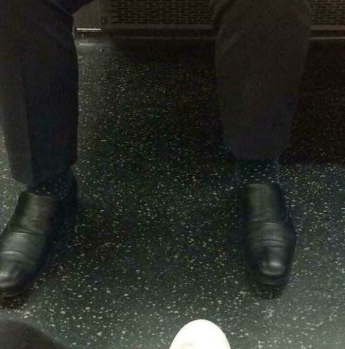 A person's legs and feet on a speckled floor, with one foot appearing unusually small, a glitch in the matrix.