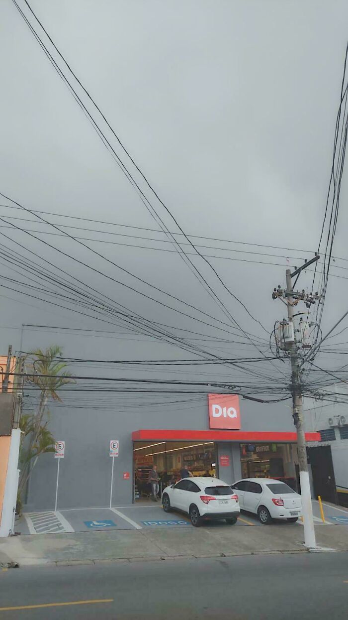 A cluttered utility pole with numerous wires, making the sky appear like a glitch in the Matrix.