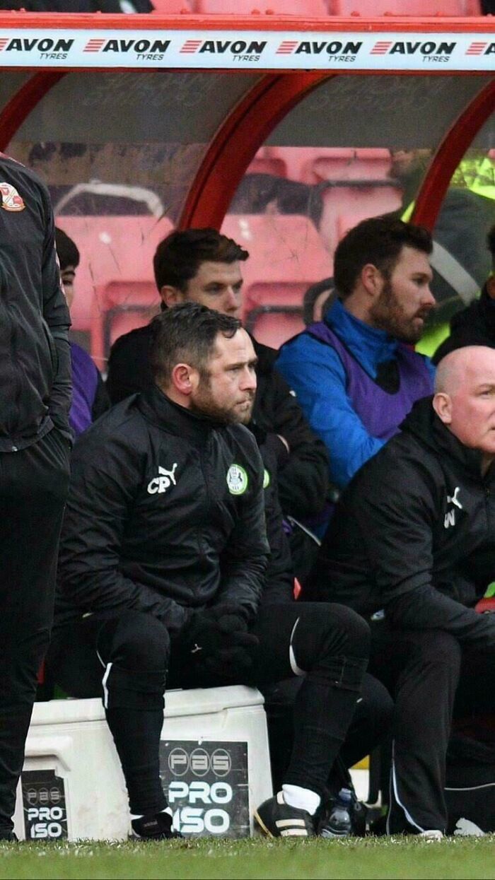 Football coach on the bench creating a Glitch In The Matrix, a duplicate figure seemingly in the background.