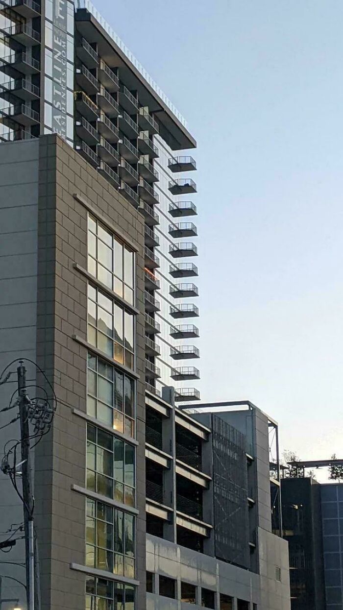 Modern buildings with balconies creating a Glitch In The Matrix, a reflection of the sky on glass facades.