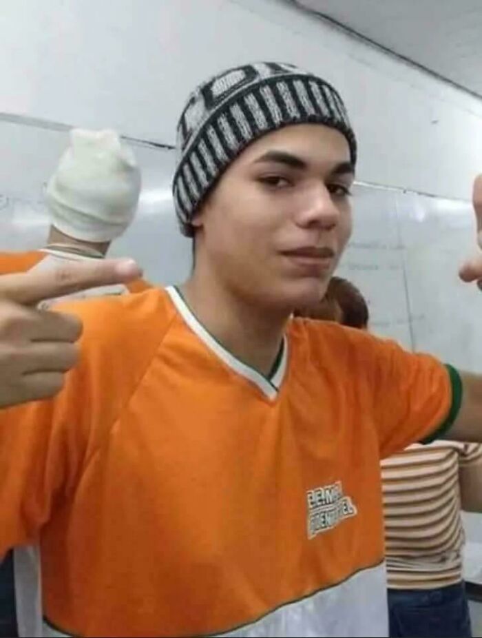 Young man with a beanie hat creating a Glitch In The Matrix by appearing to have four arms and two heads.