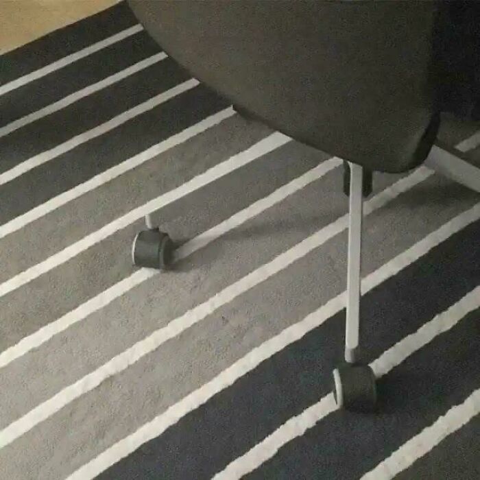 Optical illusion of a chair with a Glitch In The Matrix effect, appearing to have wheels on a striped rug.