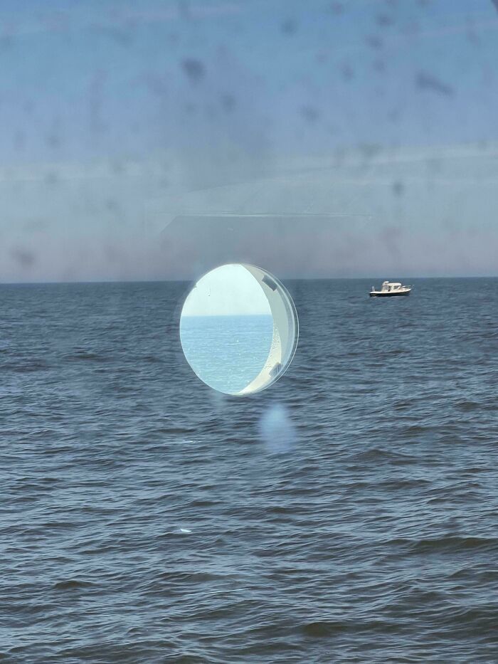 An optical illusion of a circular reflection on a calm ocean, creating a glitch in the matrix effect.