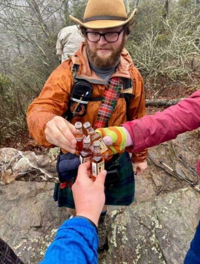 A group of hikers toasting with mini bottles, their hands creating a strange perspective, a glitch in the matrix.