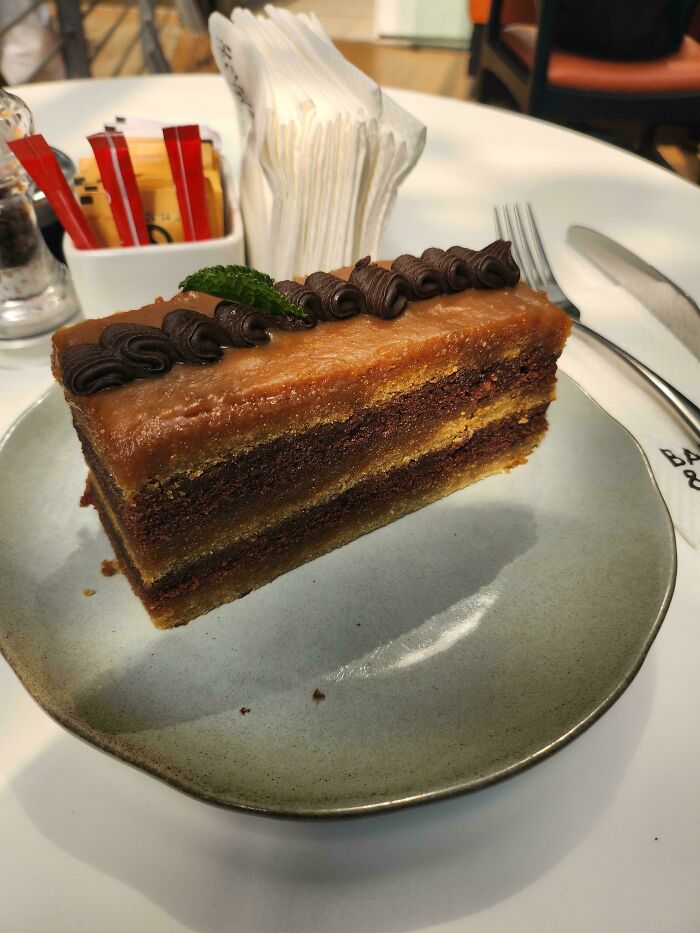 A delicious chocolate and caramel layered cake on a plate, looking like a glitch in the matrix due to its perfect layers.