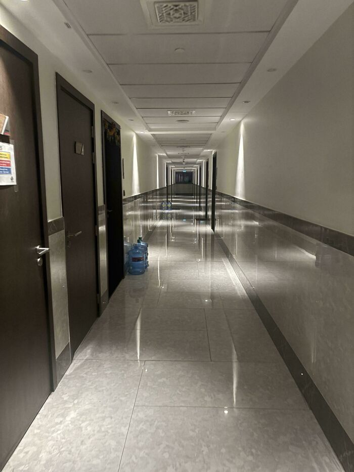 A long, empty hospital corridor with reflective floors, creating an infinite illusion, a glitch in the matrix.