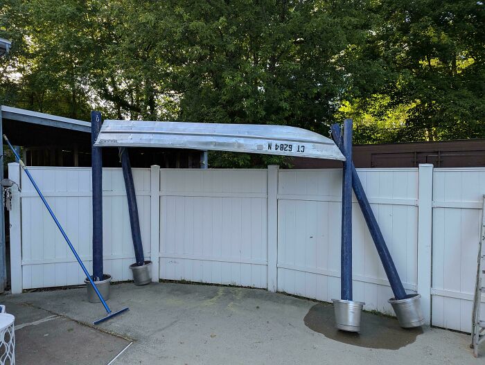 An upside-down boat used as an outdoor canopy structure, demonstrating questionable DIY projects.