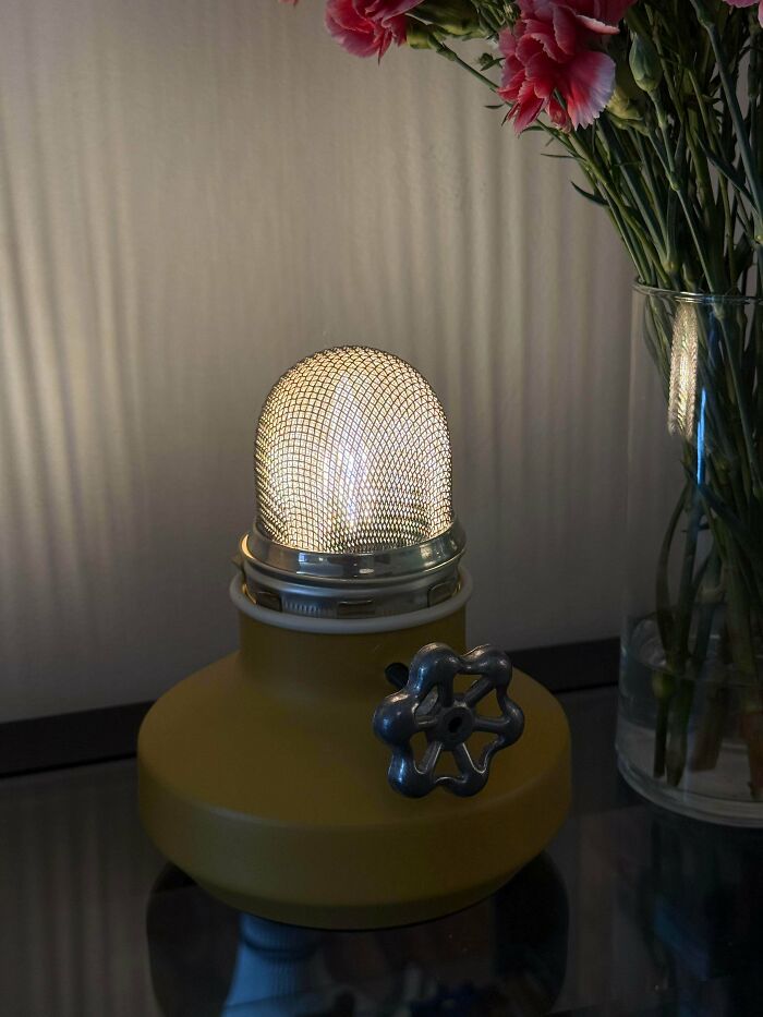 A yellow lamp made from a mesh strainer and valve wheel as a questionable DIY project.