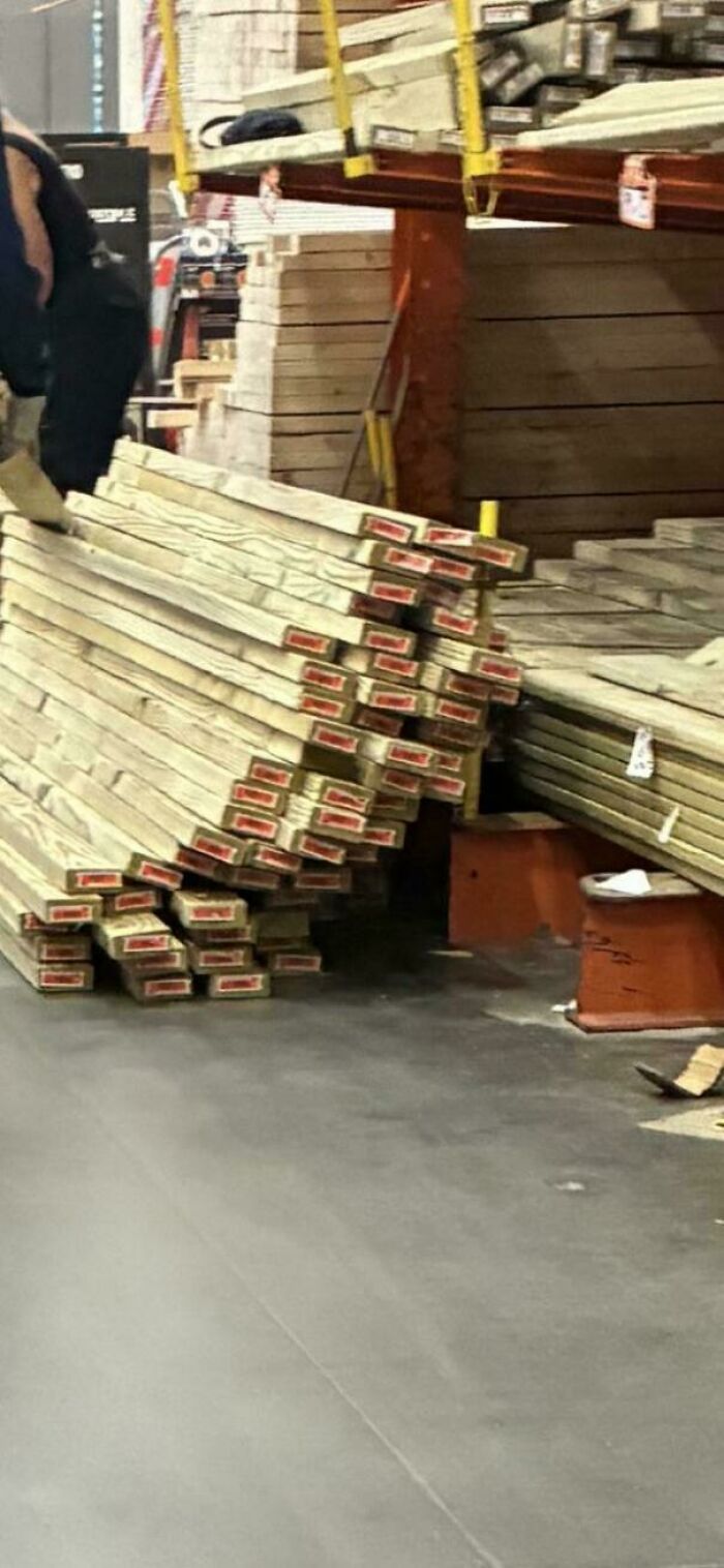 A dangerously leaning stack of lumber in an aisle, a hazard for Home Depot employees.