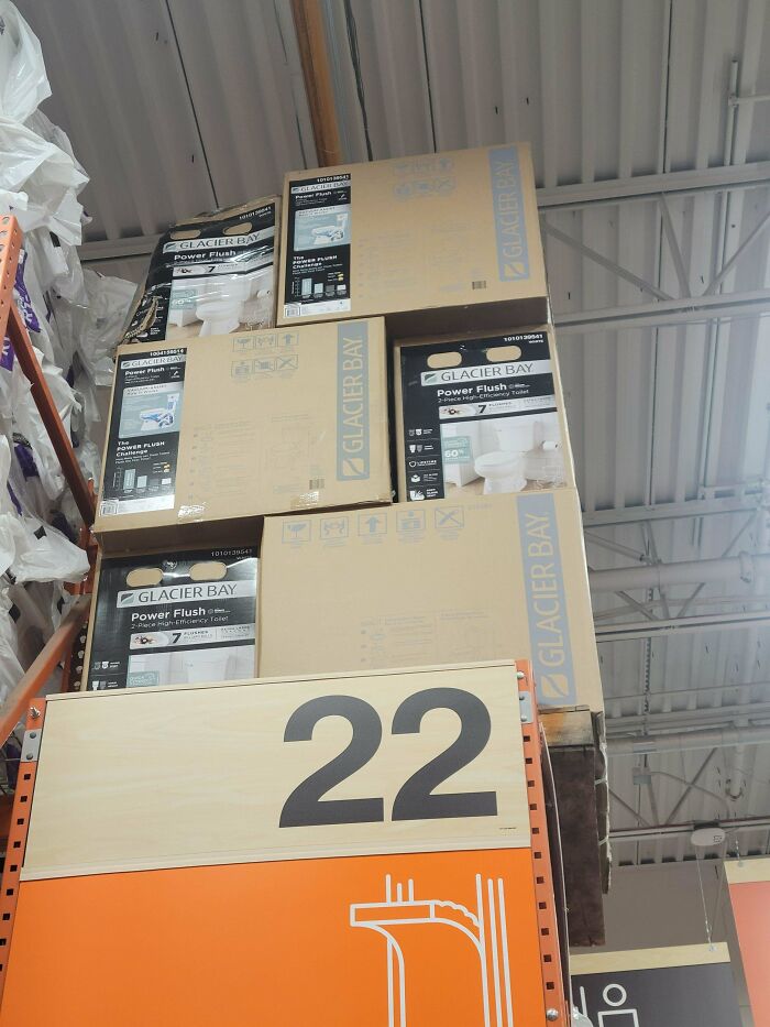 Stacked toilet boxes on a high shelf inside a store for Home Depot employees to organize.
