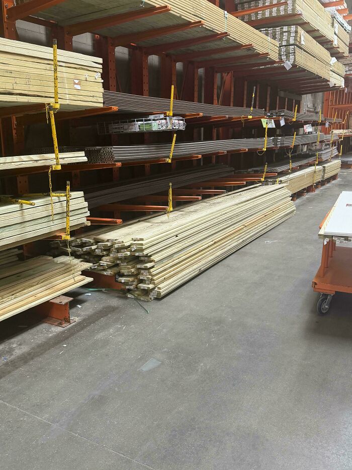 Stacks of wood planks stored on orange racking systems inside a warehouse store