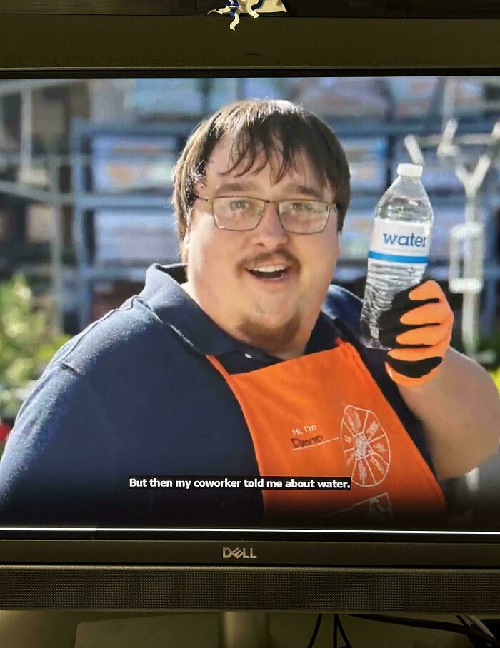 A home depot employee wearing an orange apron and holding a water bottle