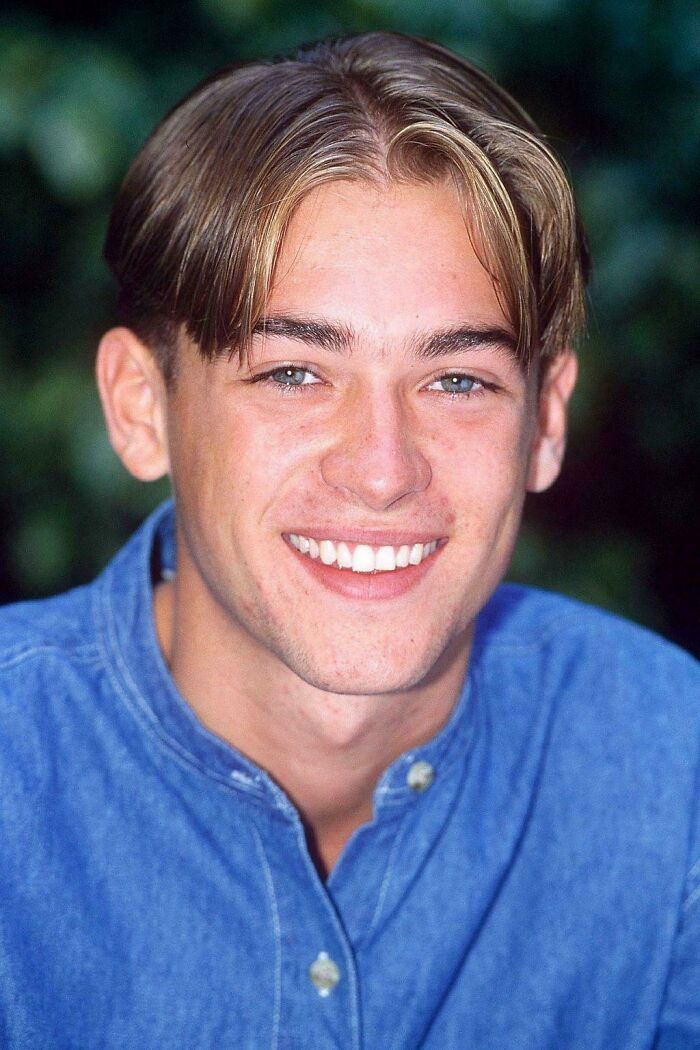 A 90s kid smiling for a nostalgic meme, with a classic 90s kid hairstyle.