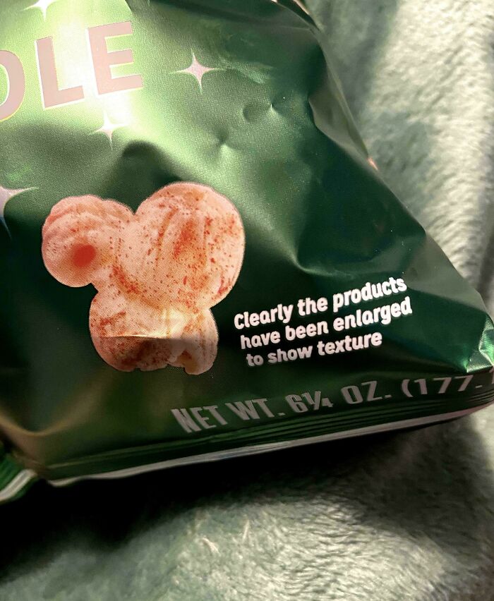 A close-up of a snack bag with a passive-aggressive note about product enlargement for texture.