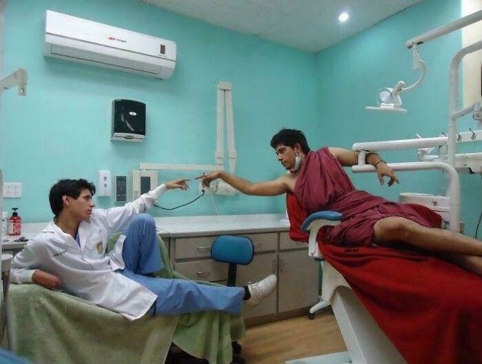 Two peculiar people recreating The Creation of Adam in a medical setting, with one in a lab coat and the other in a red toga.
