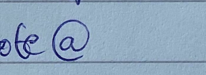 A handwritten @ symbol on a lined paper, representing a Not Interesting photo community.