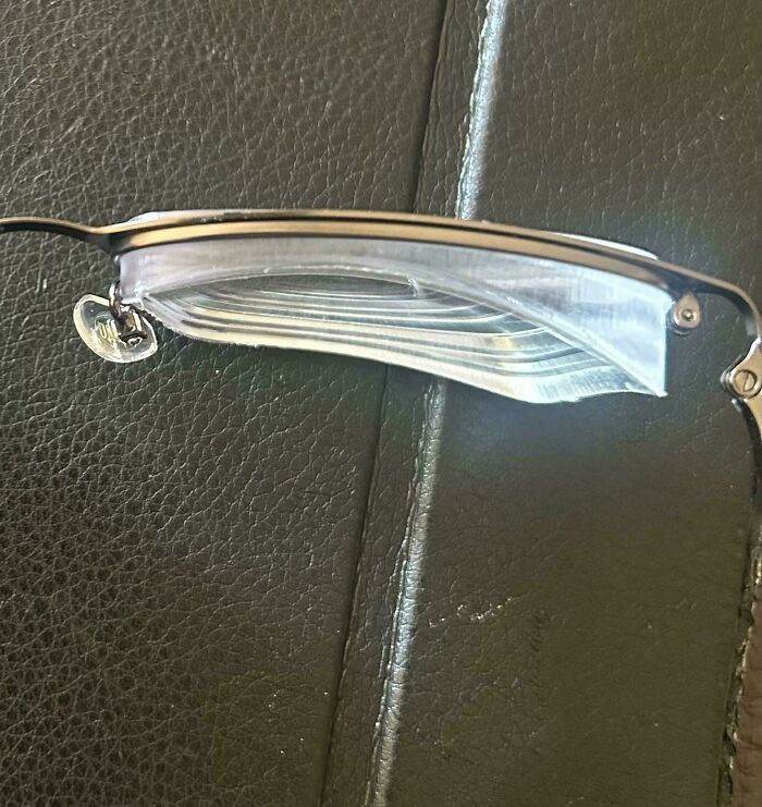 Close-up of glasses with clear, layered lenses resting on a dark surface, part of the Not Interesting community.
