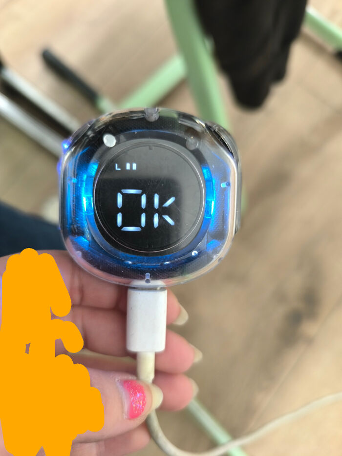 A hand holding a small digital device displaying OK with blue light, a pic from the Not Interesting community.