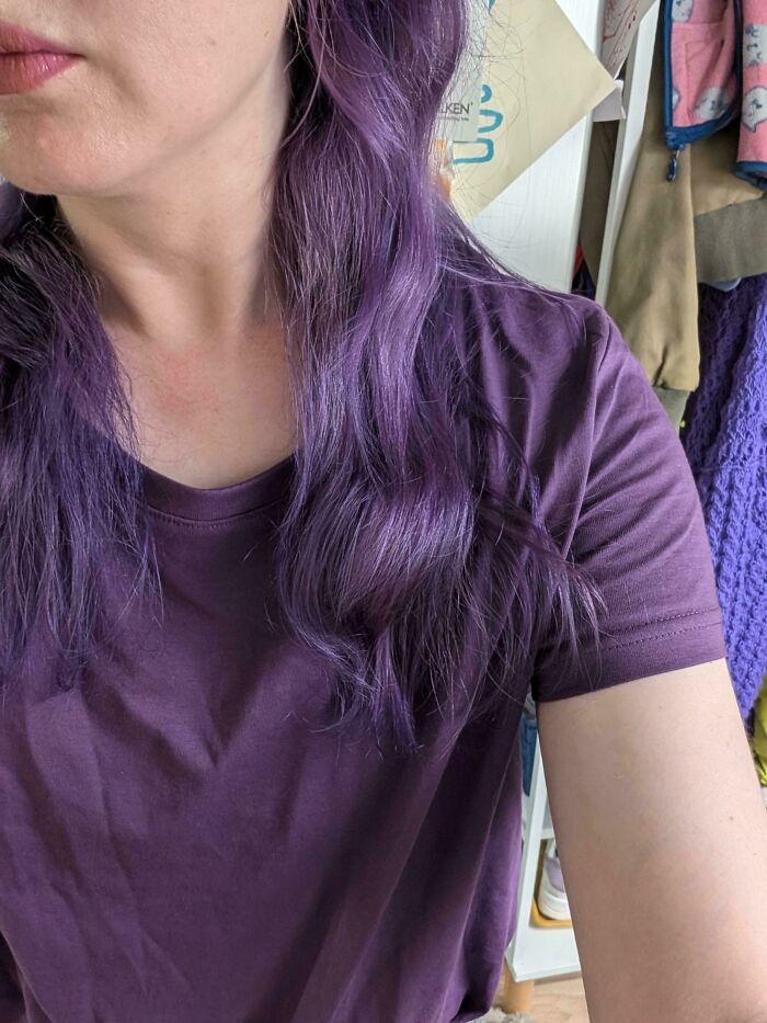 A person with vibrant purple hair and a matching t-shirt, an image from the Not Interesting community.