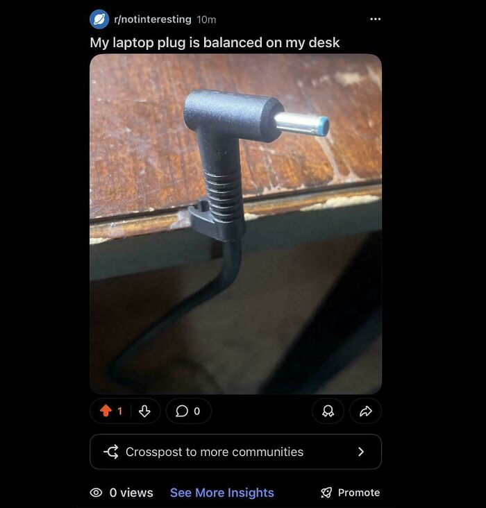 A laptop plug is balanced on a desk, a post from the Not Interesting community.