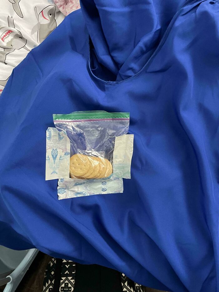 A plastic bag of crackers and some packaging for baby wipes laid out on a blue jacket, showing a not interesting detail.