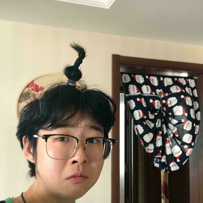A person with a single braided ponytail on top of their head, an example from the Not Interesting Community.