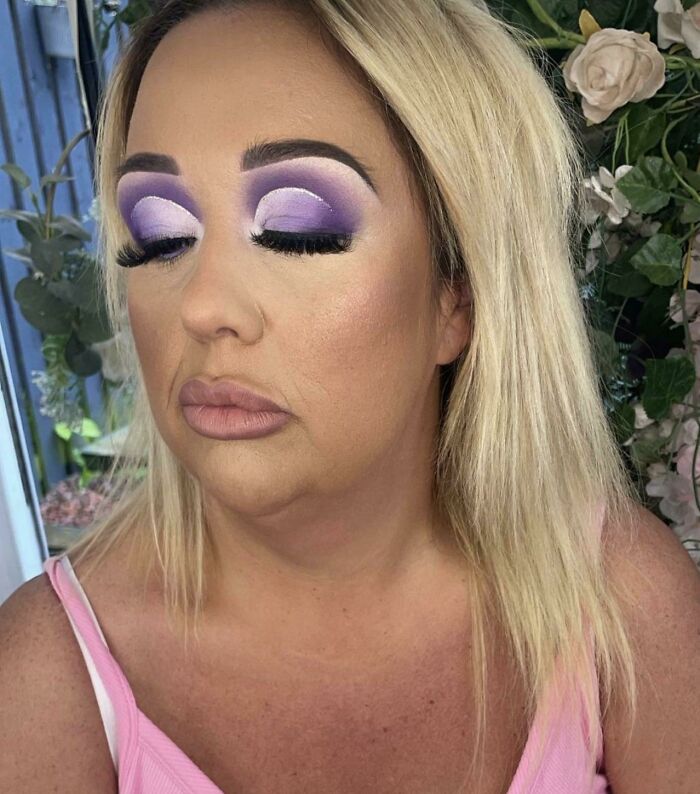 A woman with excessively dramatic purple eyeshadow and poorly sculpted eyebrows after a beauty salon visit.