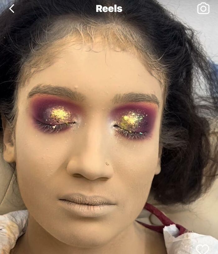 A person with heavy, glittery eyeshadow and thick foundation, demonstrating a beauty salon outcome gone wrong.