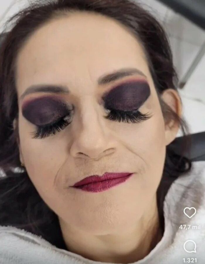 A woman with very dark, smudged eyeshadow and long, fake eyelashes from a disappointing beauty salon experience.