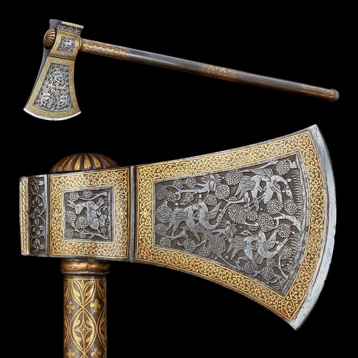 An ornate historical axe with detailed gold relief designs.
