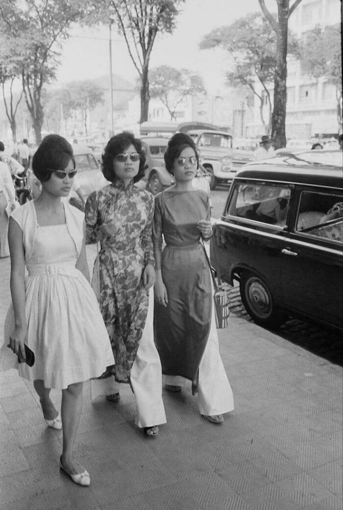 Three women walking down a street, showcasing fashion and daily life in fascinating historical photos.