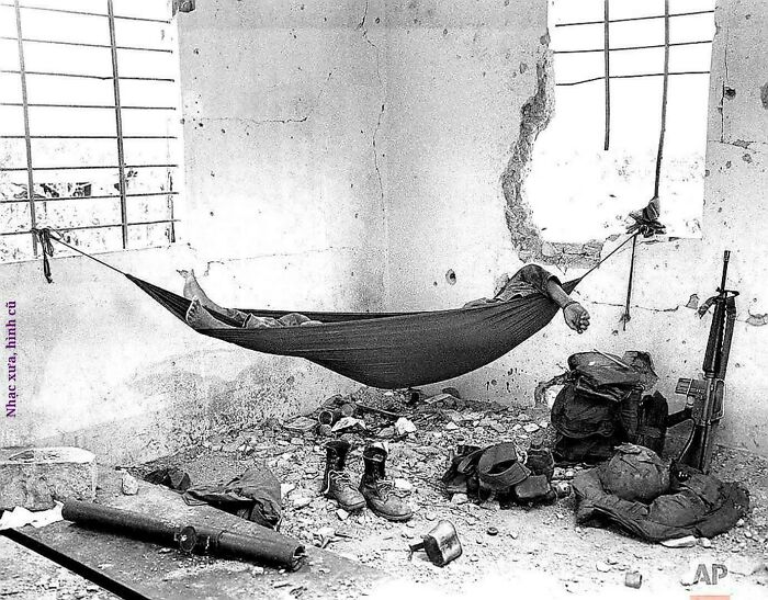 A soldier resting in a hammock amidst a destroyed room, an emotional image from historical photos.