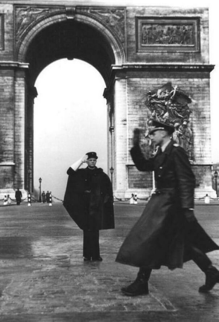 A fascinating historical photo shows two German soldiers marching in front of the Arc de Triomphe in Paris.