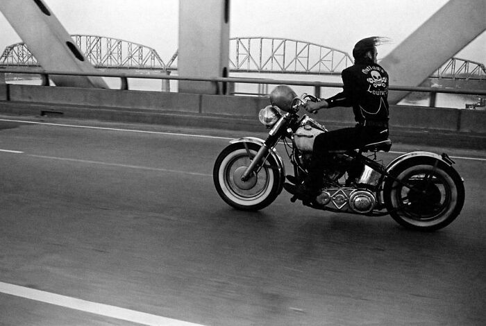 Biker riding on highway with bridge in background in real classic photo
