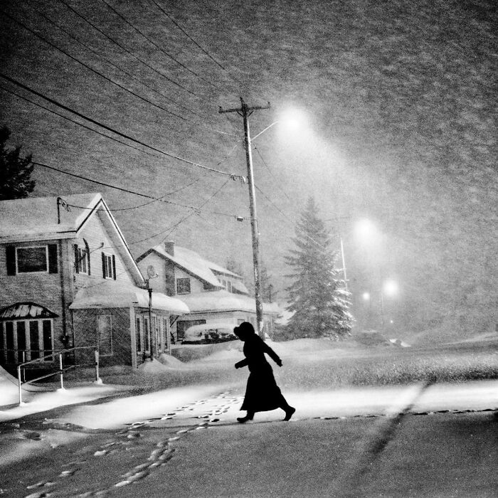 Woman walking in snowstorm at night in charming real photo of past decades
