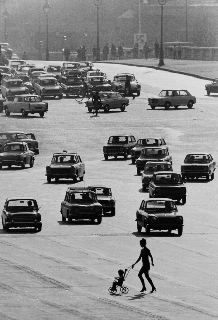 Retro busy city street with old cars and a woman pushing a child’s stroller crossing a road