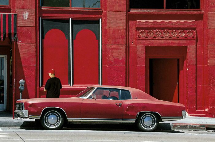 Vintage red car parked beside red building capturing special moments