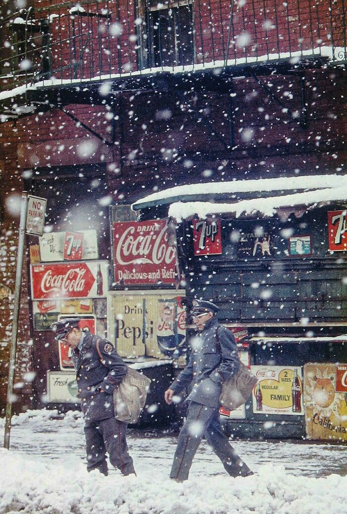 Vintage snowy street scene with mailmen walking past advertising signs