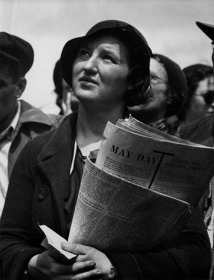 Woman holding May Day newspaper during historic labor event in past decades