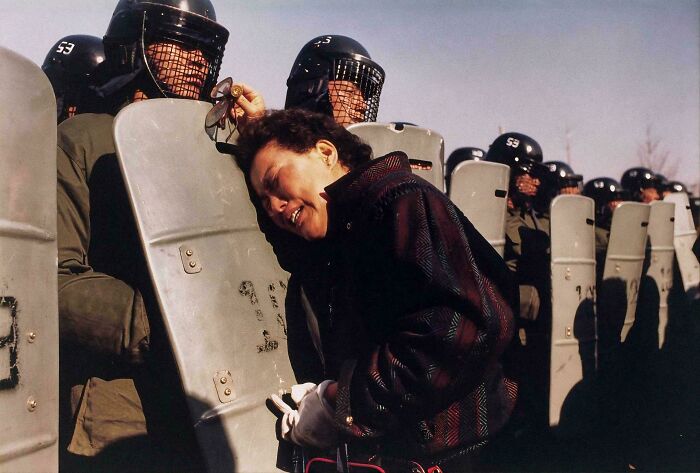 Woman crying against line of riot police with shields