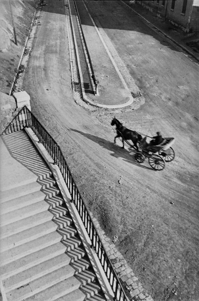 Historic photo of horse-drawn carriage on empty street with shadowed stairs